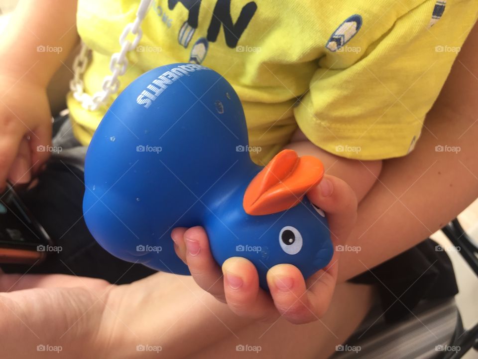 A small child holds a blue rubber duck in his hand