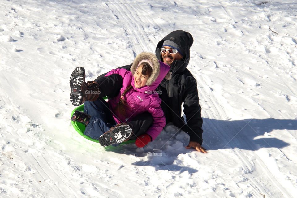 Father and daughter are having fun on a snowy hill