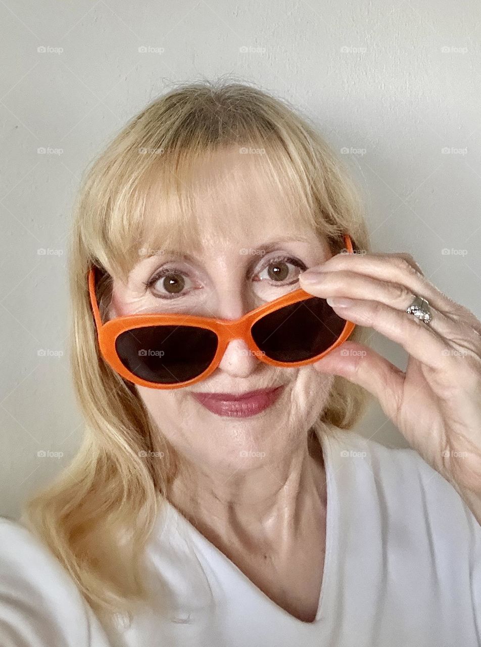 Woman looking over orange sunglasses 