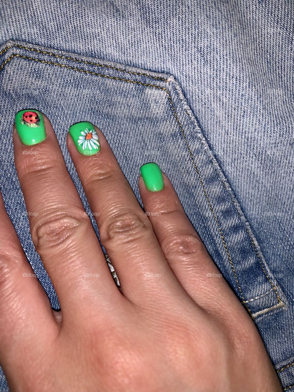hand with bright green manicure on a denim background
