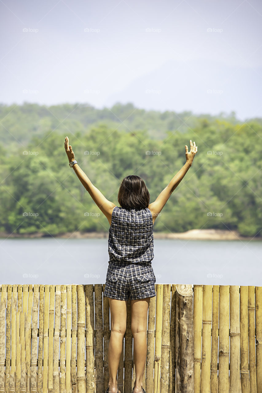 Women raise their arms Background mountains and water at Chakrabongse reservoir , Prachinburi in Thailand.