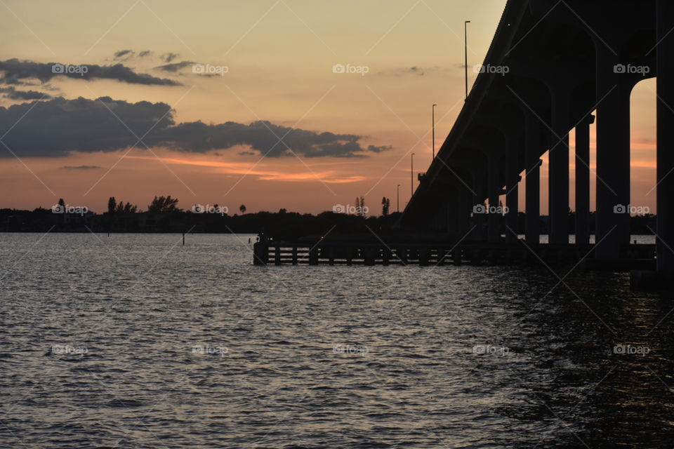A view of the water at sunset with the bridge to the right.
