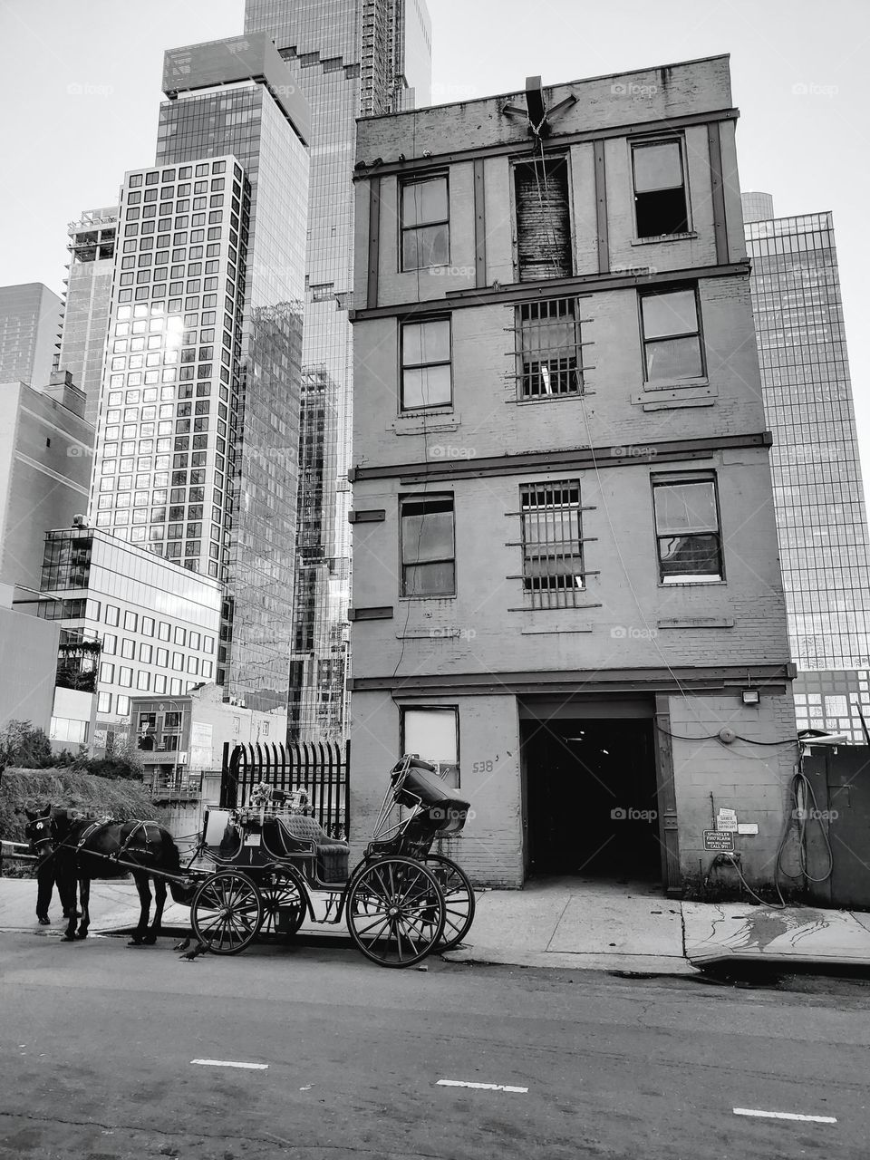 A horse drawn carriage parks in front of a dilapidated building in Manhattan on a cold late fall afternoon