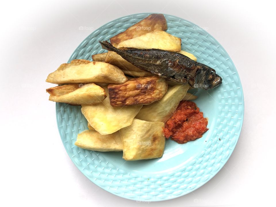 Fried sliced yam,friended pepper and fried fish in a plate which is a native Ghanaian food for consumption 