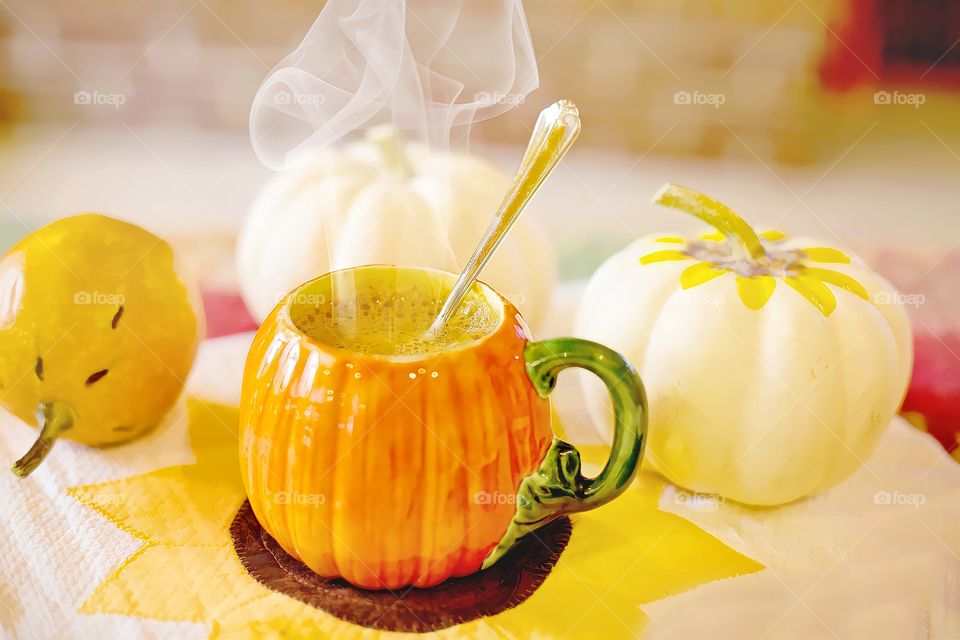 Pumpkin spice latte with spoon. 
Close up of white pumpkins with cup of hot pumpkin spice latte on table.