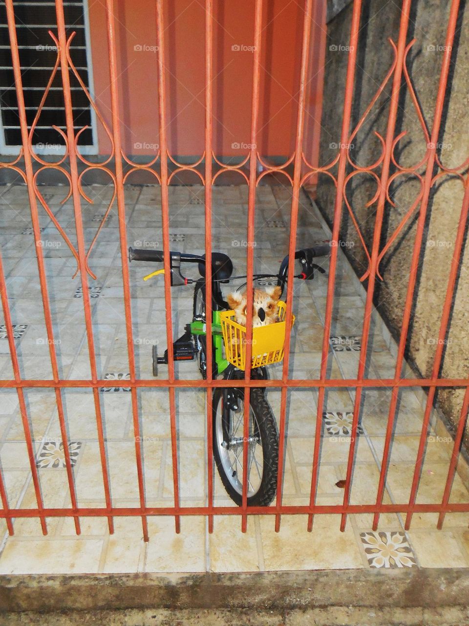 Lonely Bicycle on a Brazilian house, behind bars, with a plushie on the front