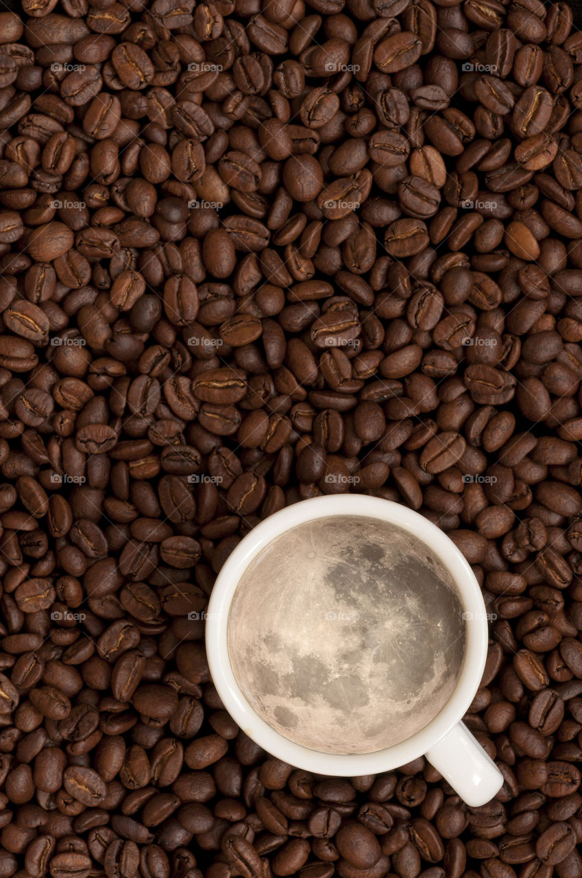 Cup of coffee with full moon as crema among coffee beans