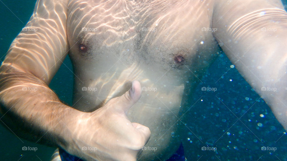 Man diving in the ocean, male underwater smiling,swimming and relaxing in big blue sea with his waterproof camera