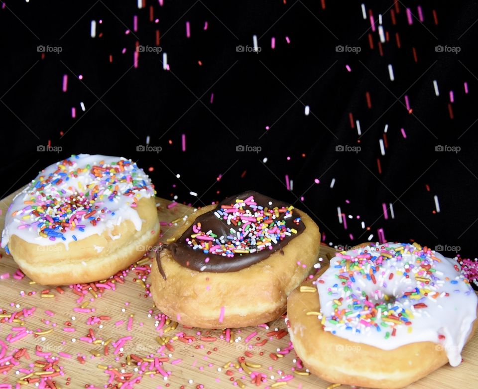 Donuts with icing and sprinkles, adding more sprinkles 