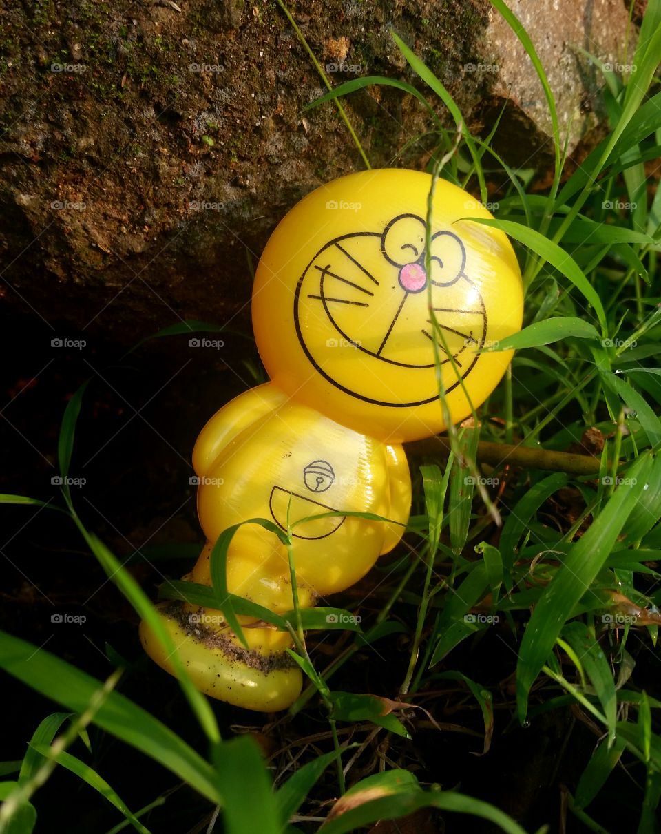 doremon toy, stone and grass in morning sun