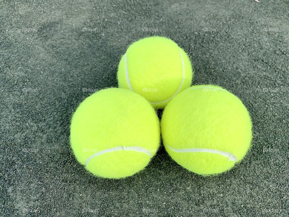 Three tennis balls on the clay court.