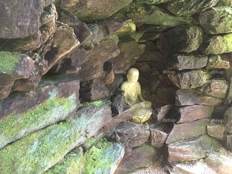 A praying Buddha hidden in a rock wall.