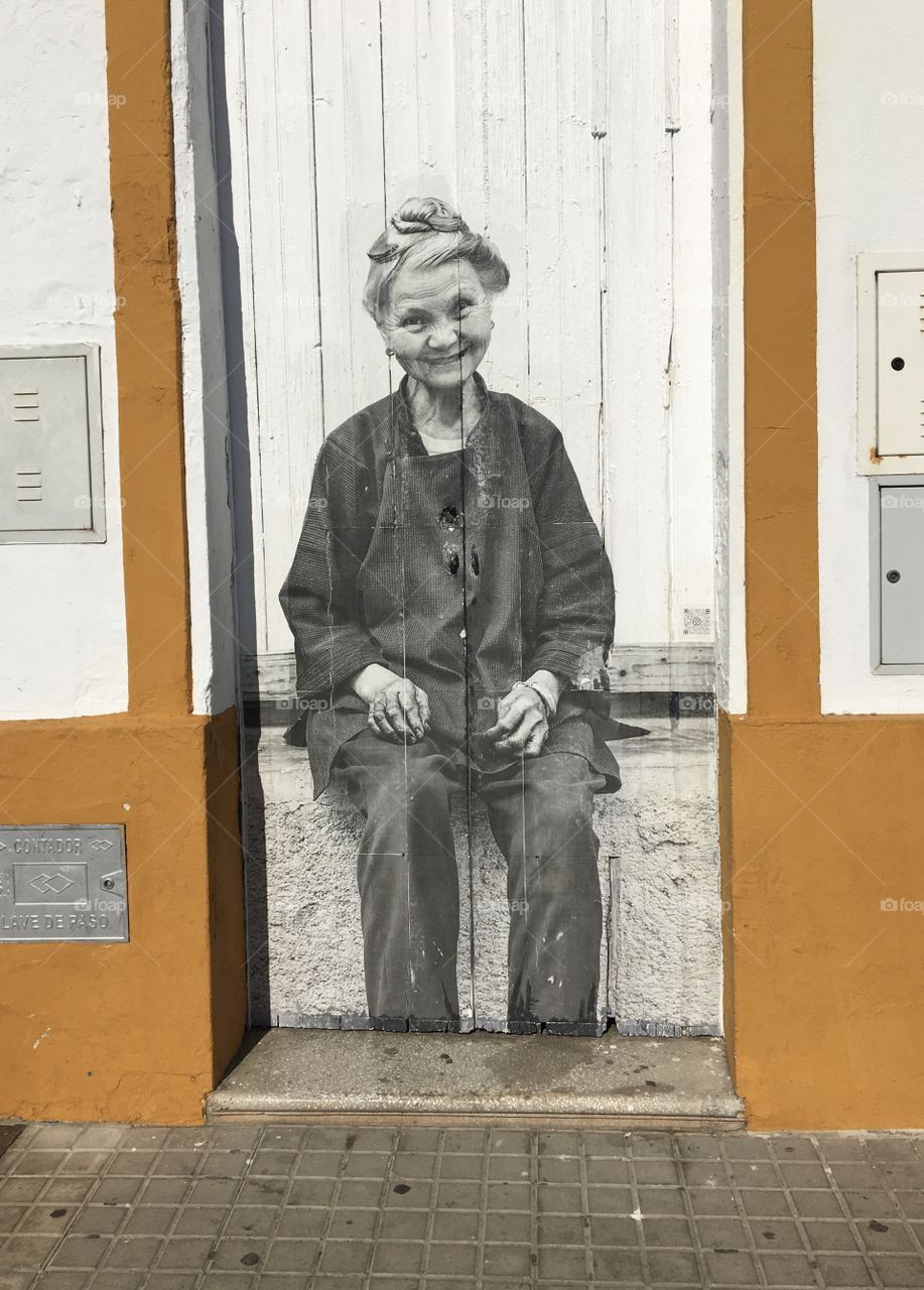 Old woman’s smiling face pictured on a wooden door 