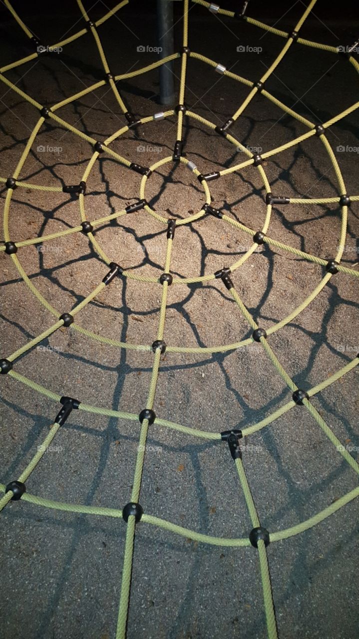 Spiderweb for climbing and playing over a sandbox in a playground.