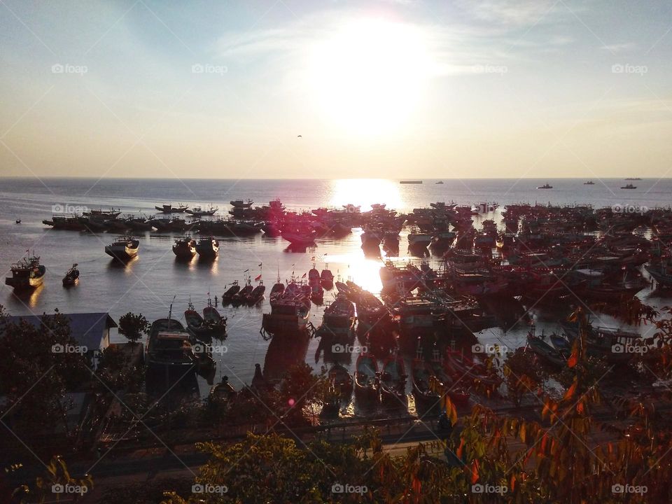 Sunset view on the beach with many fishing boats leaning, photo taken from the top of the hill