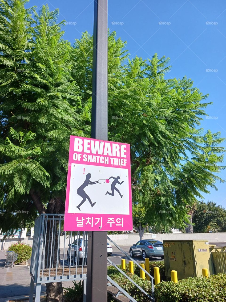 Funny parking lot sign of danger. Picture of person trying to snatch personal belongings.  Sign reads Beware of Snatch Theft.