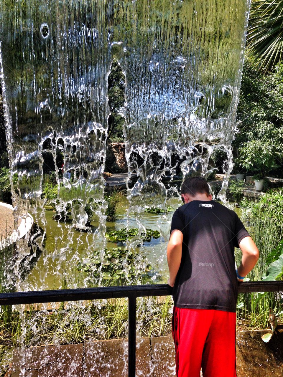 Under the falls. Boy by a waterfall 