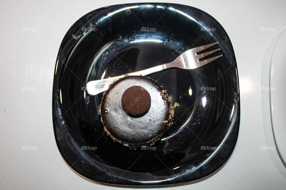 A chocolate cake with walnuts on a black plate