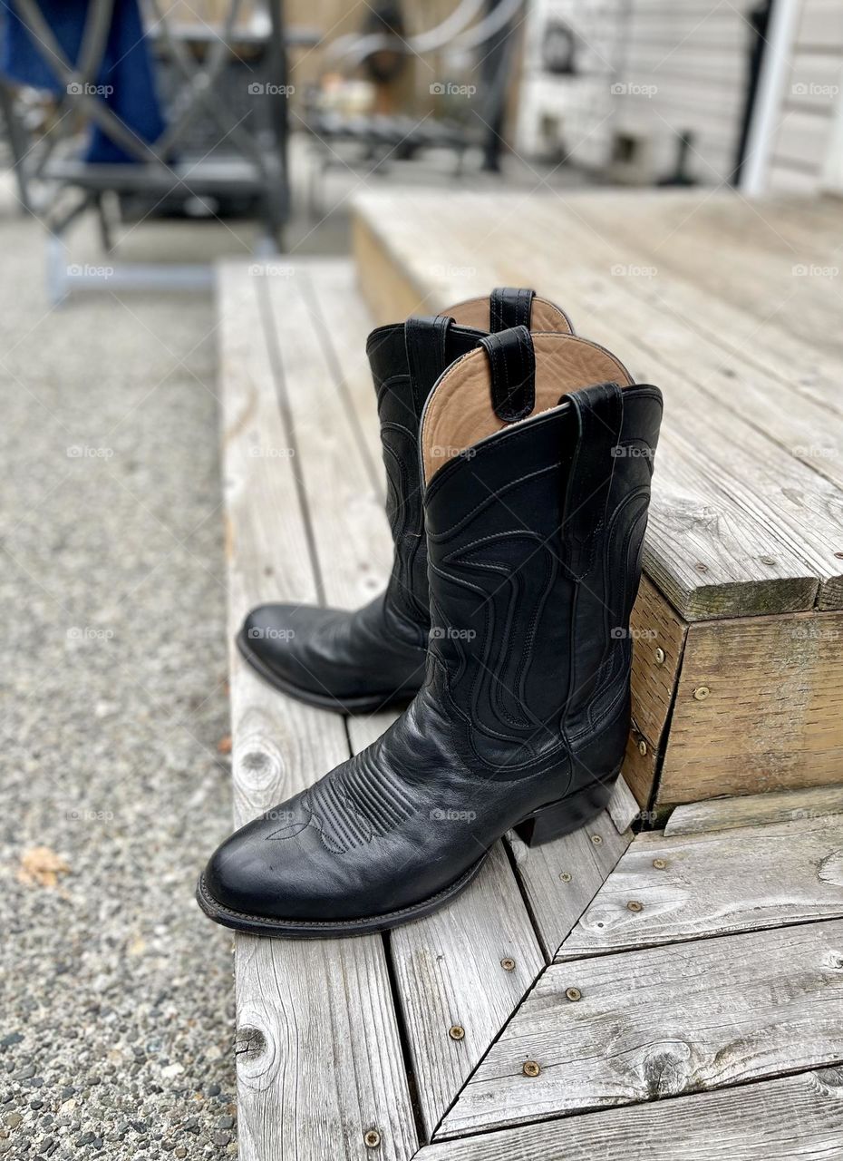 Black cowboy boots on the wooden porch 