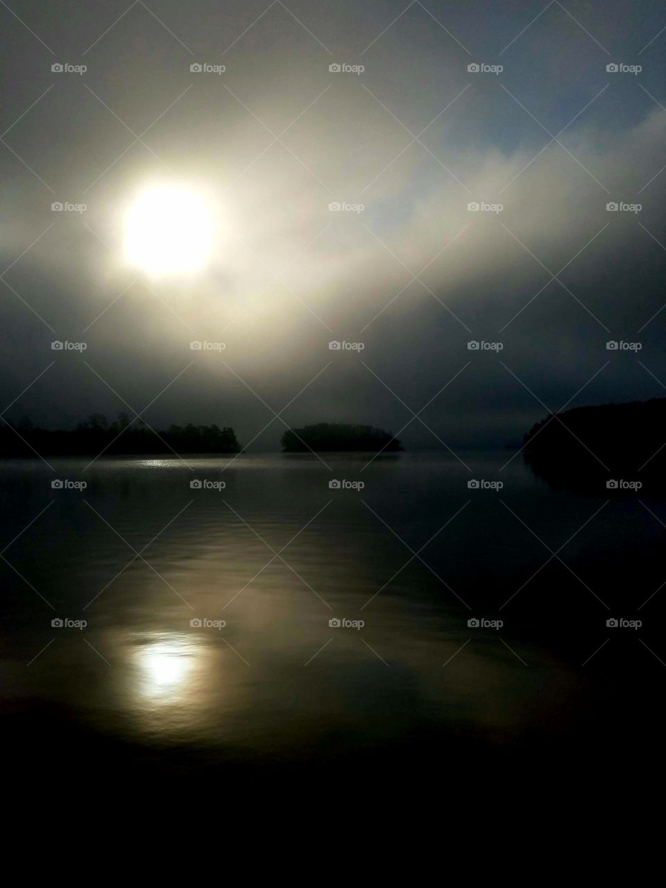 foggy morning on the lake with reflections of the sun.