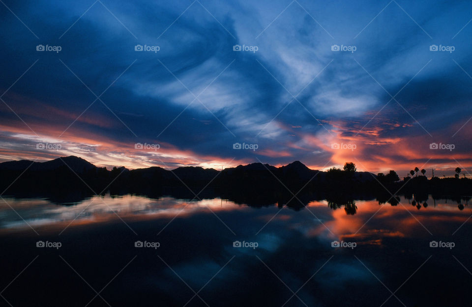 A beautiful western sunset casts its reflection onto a pond in Arizona.