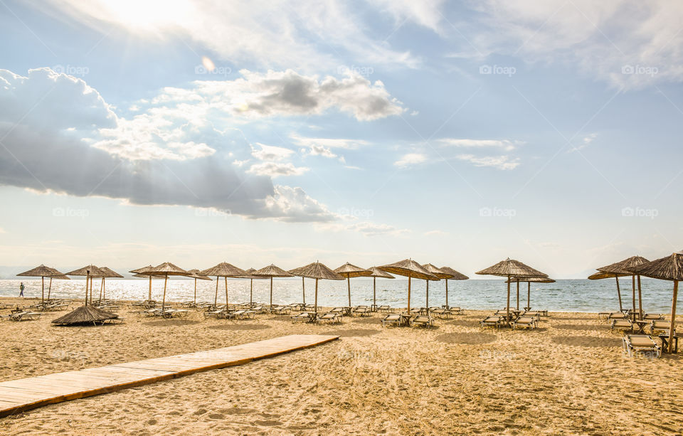 Straw Beach Umbrellas And Sunbeds On The Beach
