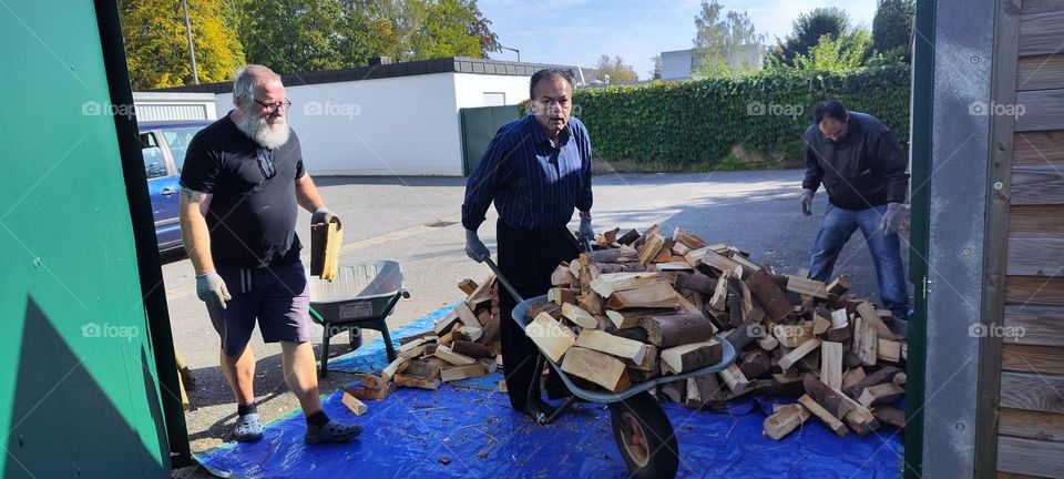 The wood delivery for the winter from the „Bayerischer Wald“, the Bavarian forest is here and all available men are helping to pick it up, move and stack it properly in a place designated for it. 2023. Hypnotic Productions