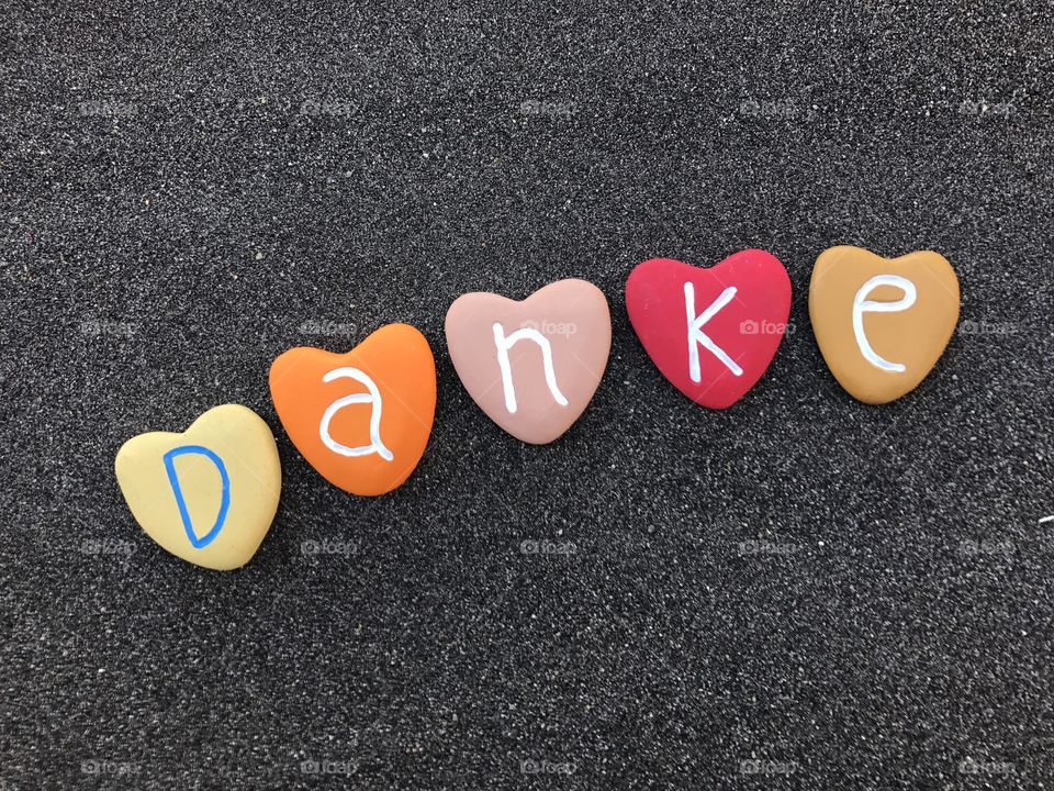 Danke, german thank you with colored heart stones over black volcanic sand