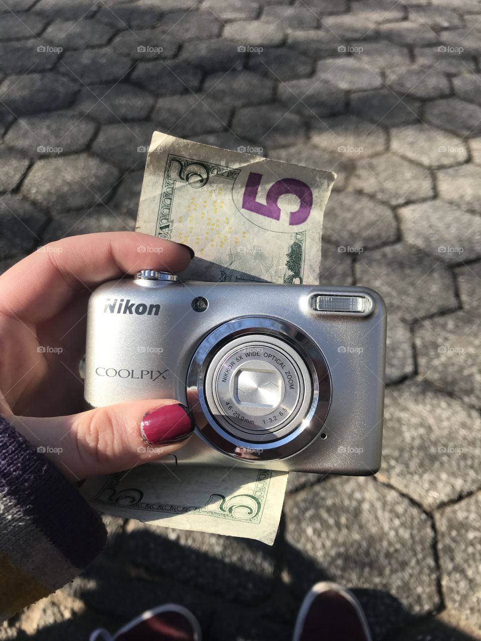 From snapshot to five dollar bill: an image of a Nikon point-and-shoot camera rested on a five dollar bill. 