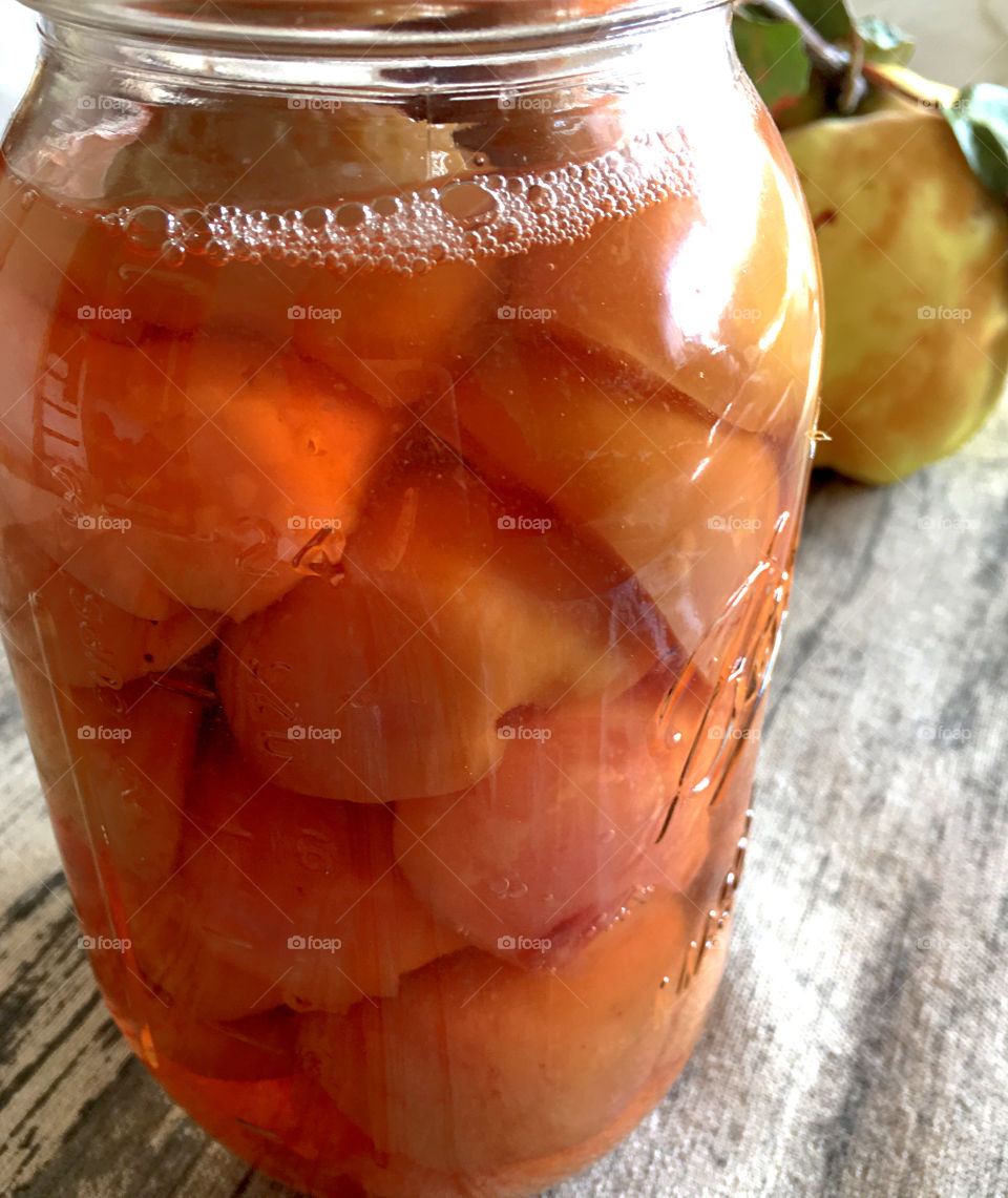 Canning and cooking up quince fruit home preserves in canning jar as well as the actual quince fruit beside