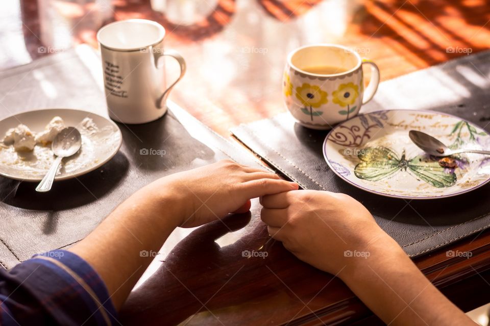 Couple having breakfast together holding their hands 