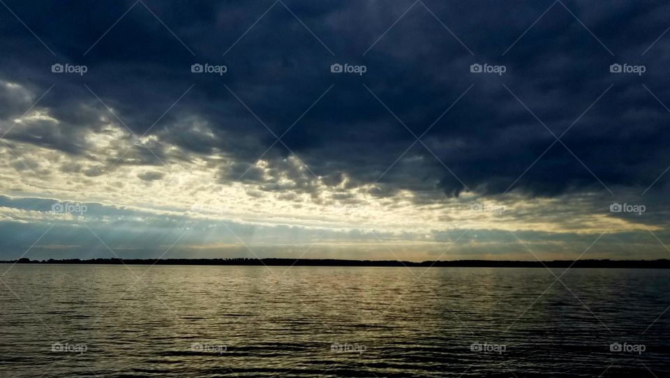 rain clouds with sunbeams over lake