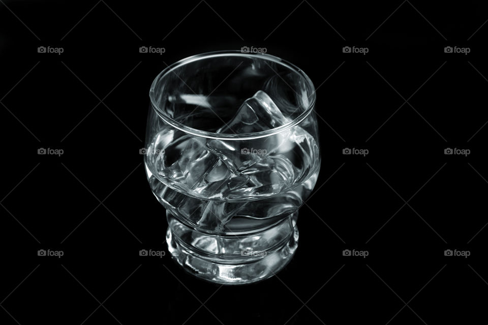 Chilled water glass with ice cubes on black background