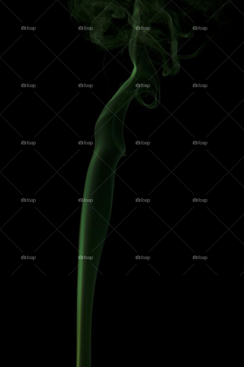 Green abstract smoke swirling on black background