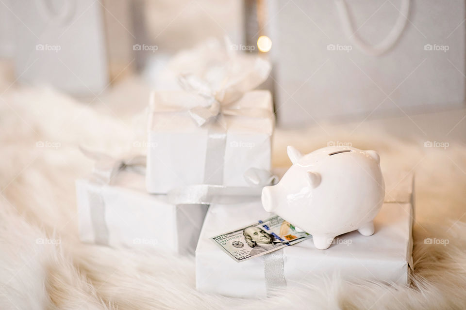 piggy bank with 100 dollars banknote in festive New Year atmosphere of scenery.  Magical bokeh with Christmas tree and bright lights.