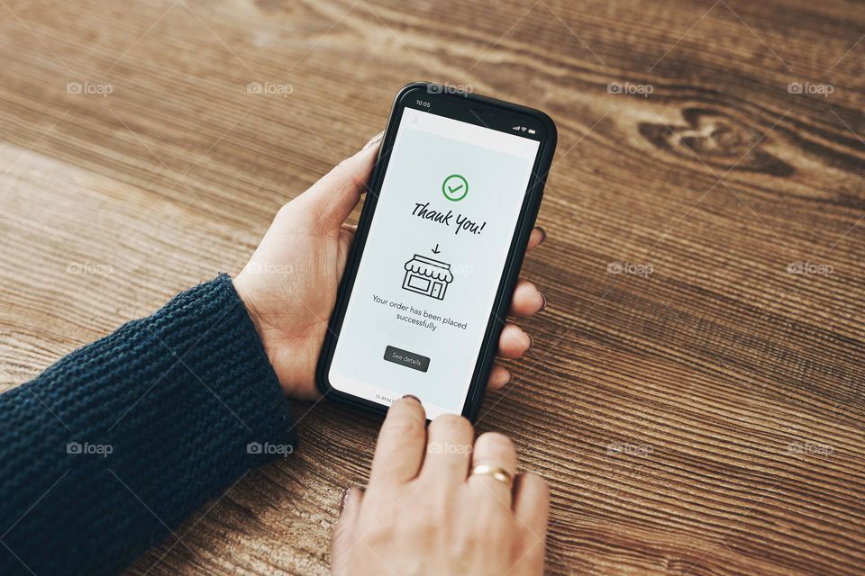 Shopping online. Ordering product online using smartphone. Female hands using smartphone for online shopping. Order confirmation - thank you. Your order has been placed successfully - displayed in store app on smartphone screen