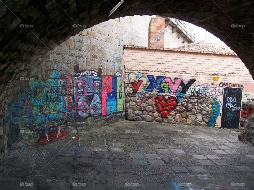 Alley under a bridge with colorful graffiti 