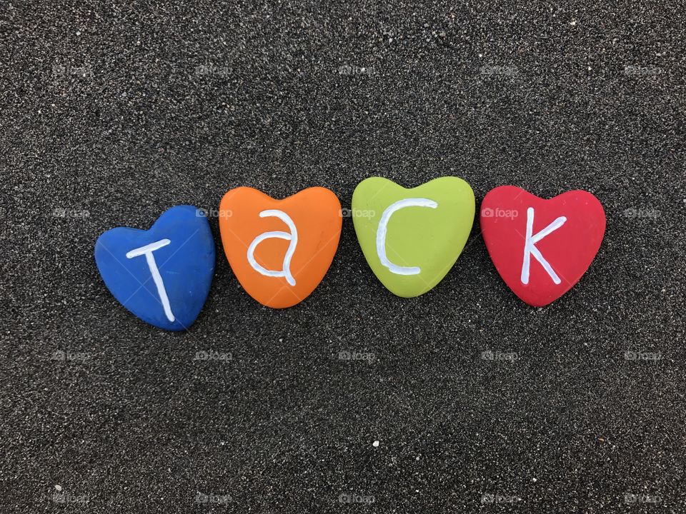 Tack word with colored heart stones over black volcanic sand