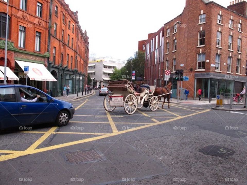 Old meets new - horse carriages and cars along the same urban road junction 