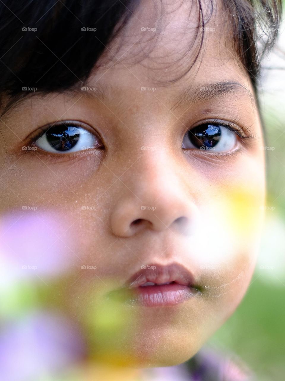 cute little girl looking at camera with flower foreground.