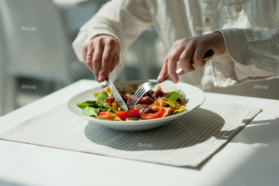 close-up of a young man eating a salad in a light kitchen