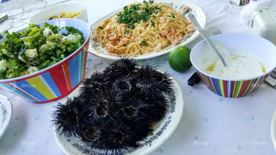 Having a healthy mediterranean dinner with sea urchins,spaghetti with shrimps,tzatziki and a salad in Artemida,Greece