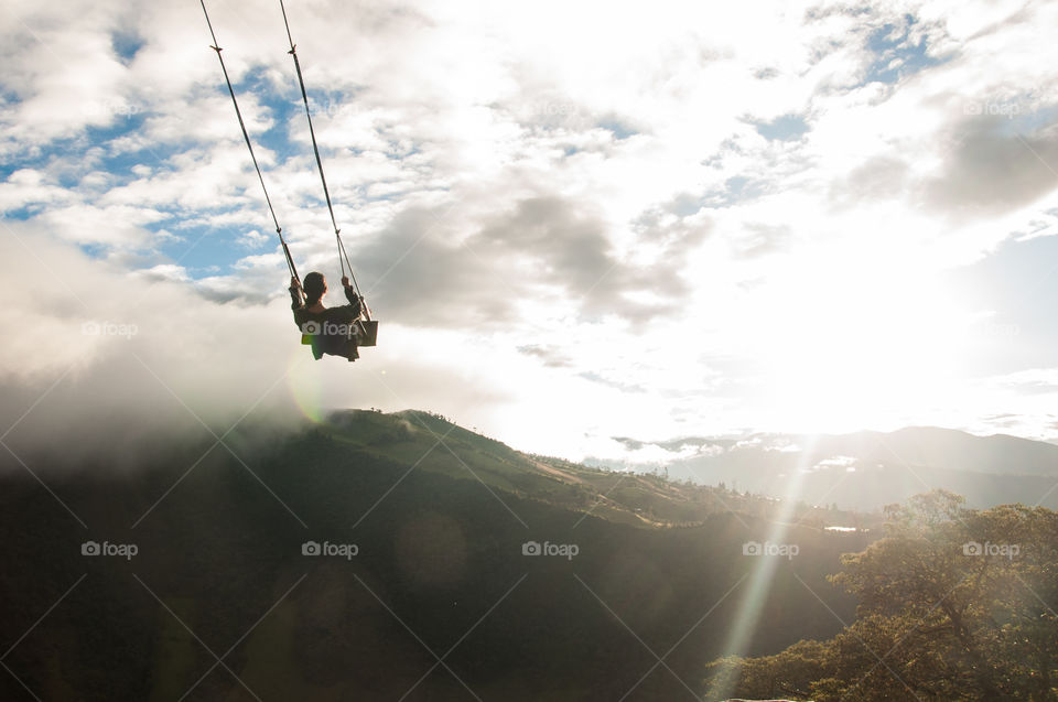 Woman on a swing at the edge of a cliff at sunset 