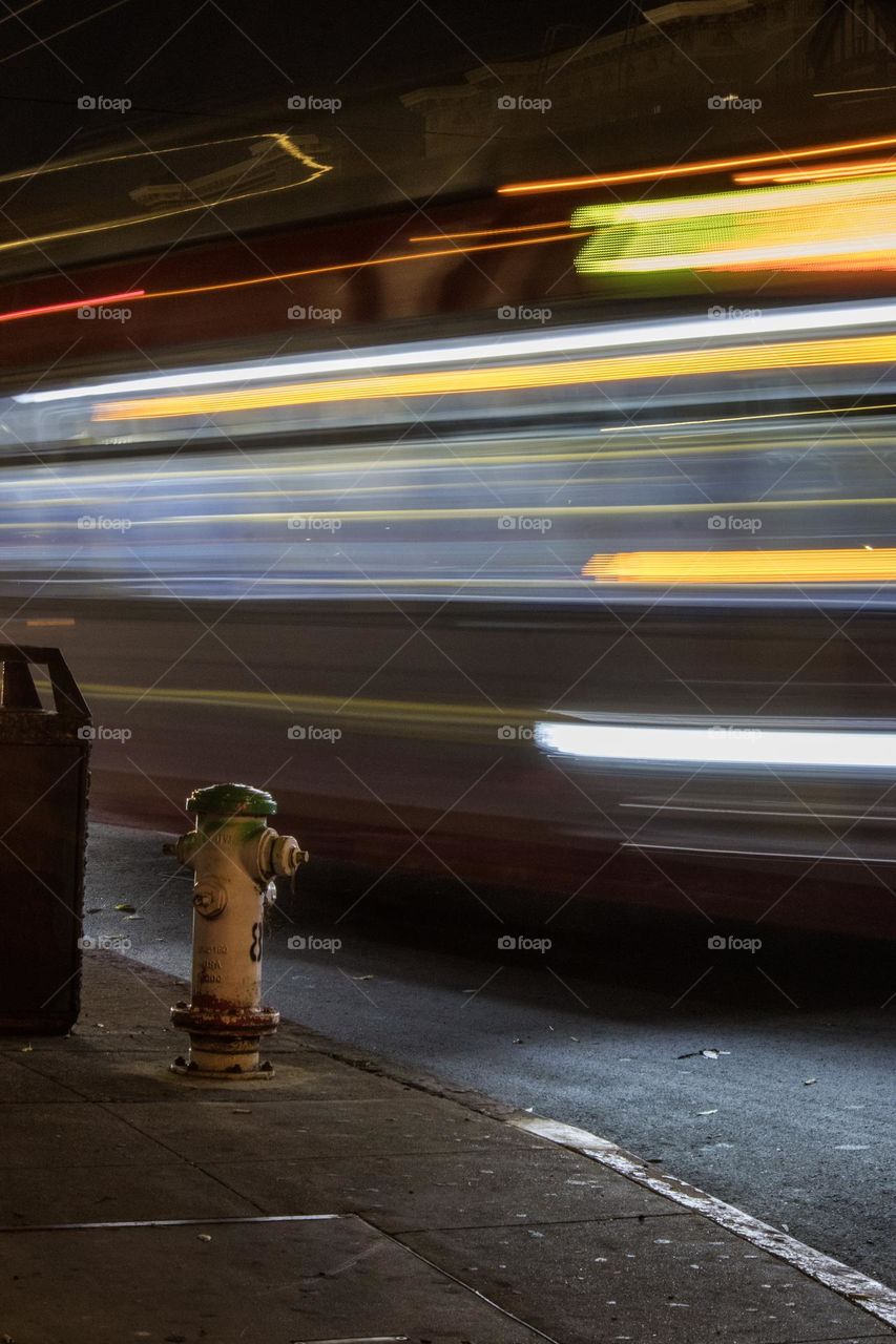 Long exposure of the 22 Fillmore bus at night in San Francisco on Fillmore Street and Bay Street at the bus stop as it moves down the street