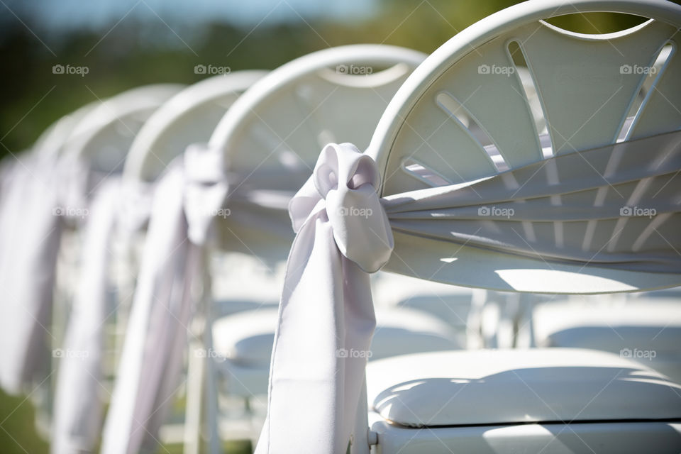 white ribbons and bows on white weddi g ceremony chairs