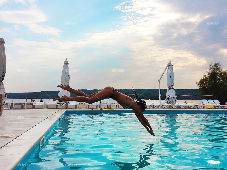 Young woman jumping at the swimming pool 