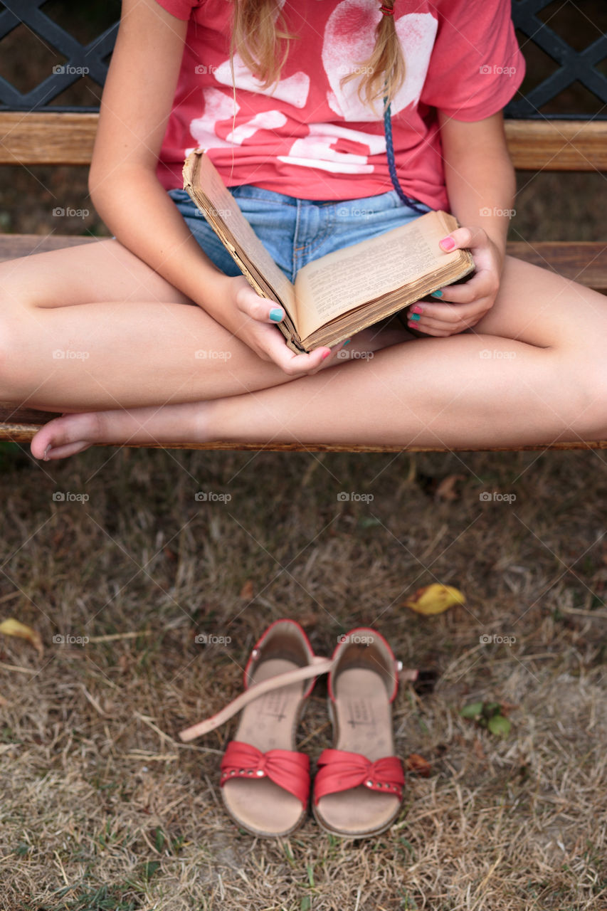 Girl reading a book on a bench