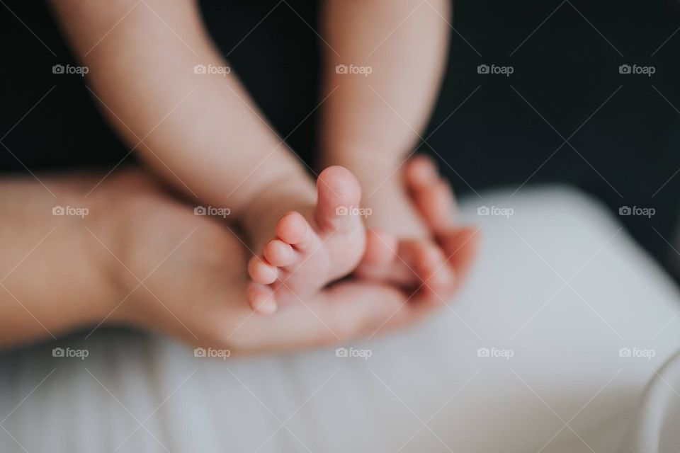 New him holding tiny baby feet in her hands, cradling the wiggly toes for a cute photo.