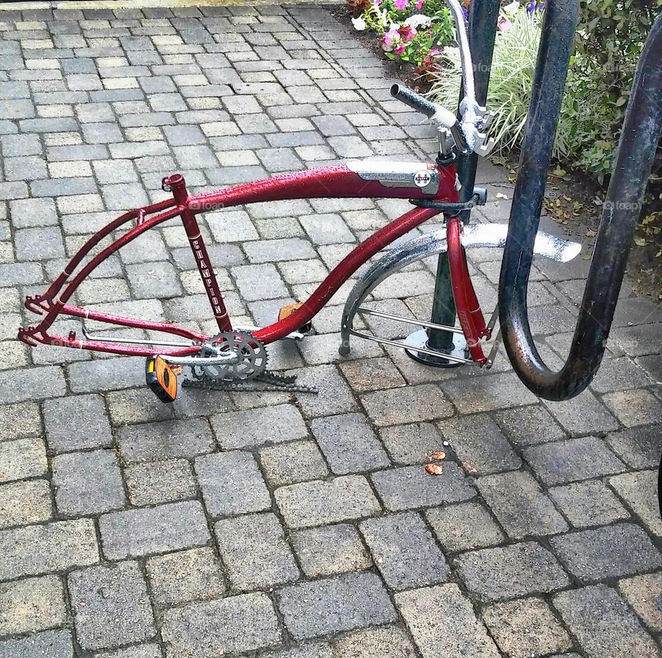strip down bicycle locked to a bicycle rack on a rainy day