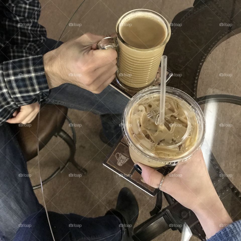 Hands Sharing coffee together at a table one hot one iced 